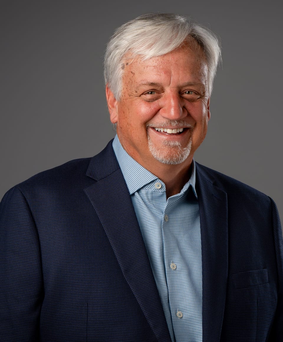 Tim Zizack smiling in a navy blazer