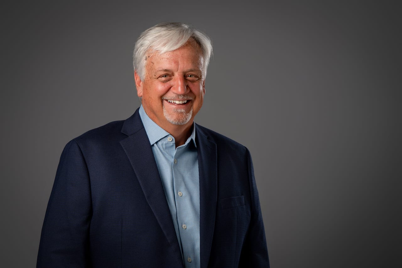 Tim Zizack smiling in a studio portrait